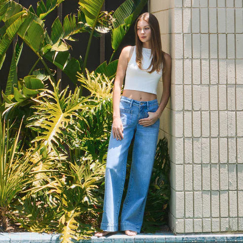 Model in white crop top wearing Flying Monkey Dignity high-rise patch-pocket wide-leg denim trousers.