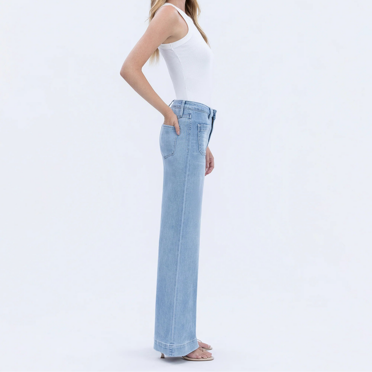 Side view of a woman wearing light-wash Dignity high-rise patch-pocket denim trousers with a wide-leg silhouette.