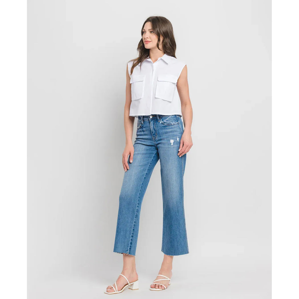 Model wearing Flying Monkey Supported High Rise Slim Wide Leg jeans in blue denim with distressing and raw hem.