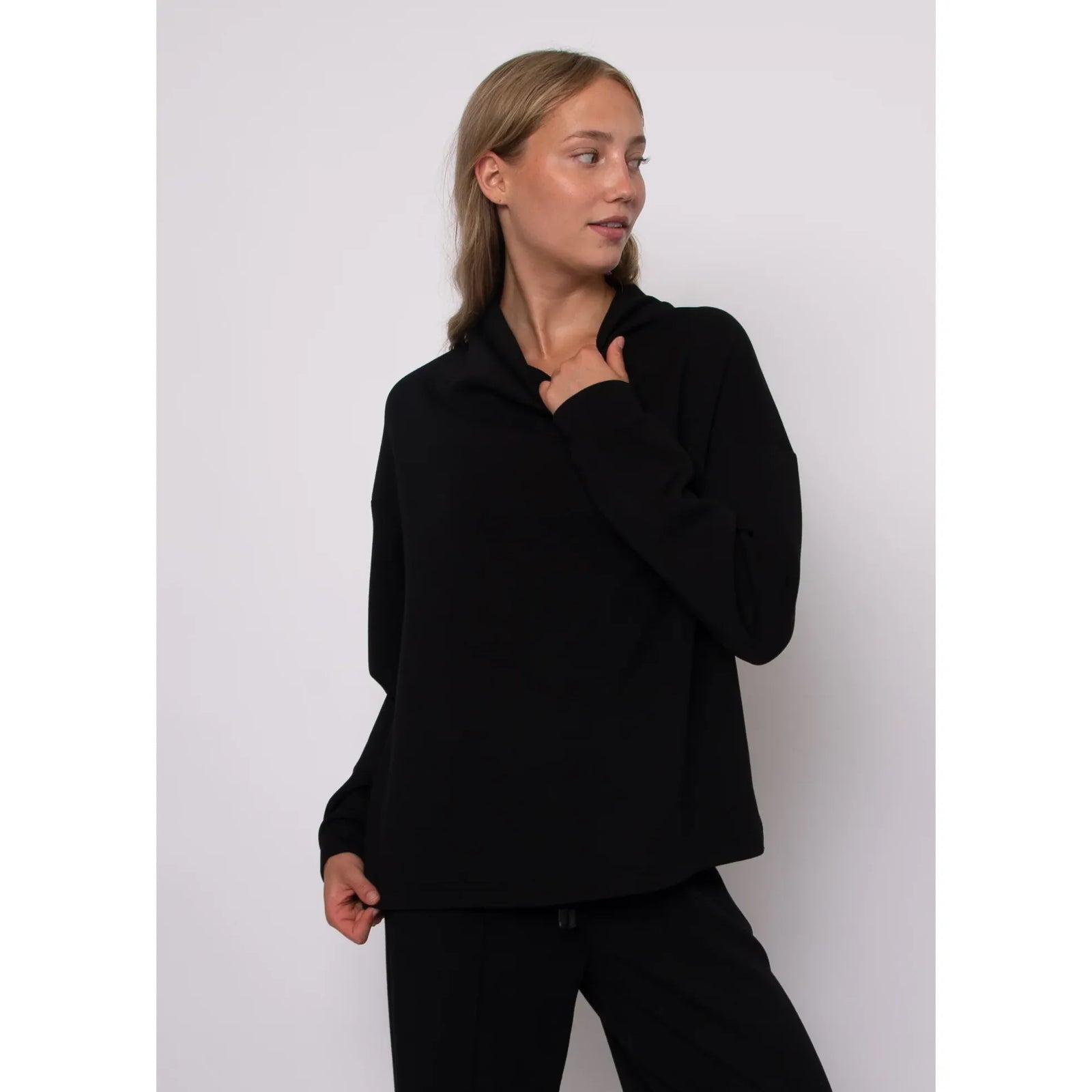 Black soft knit funnel neck top with long sleeves, featuring a refined stand-up collar and effortless everyday style.