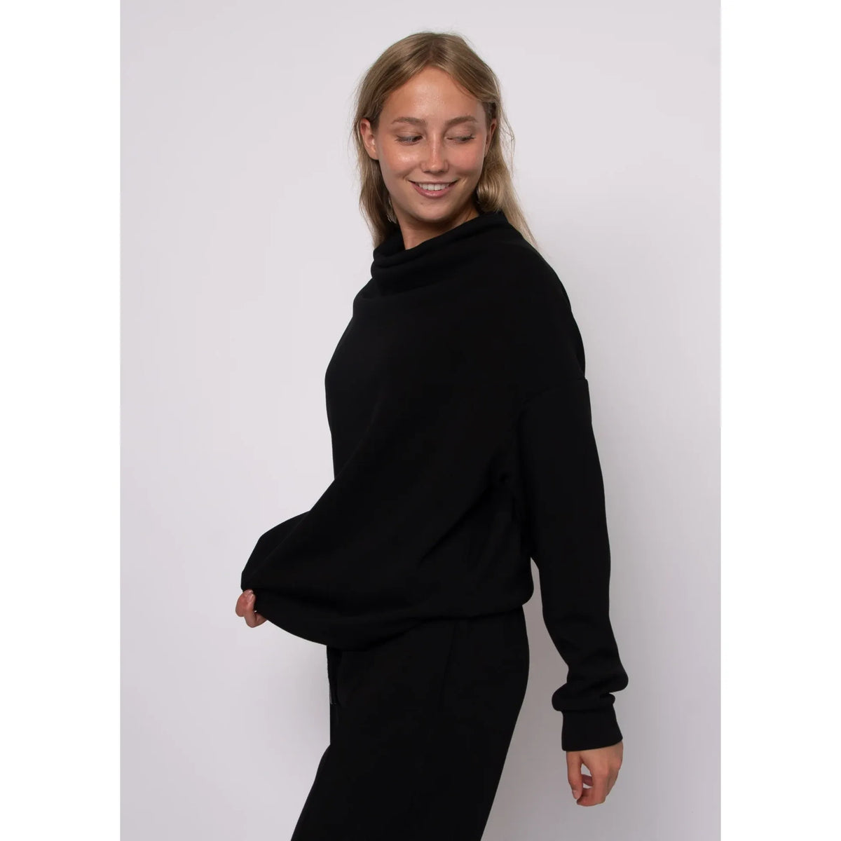 Black soft knit funnel neck top with long sleeves and cozy stand-up collar for effortless everyday style.