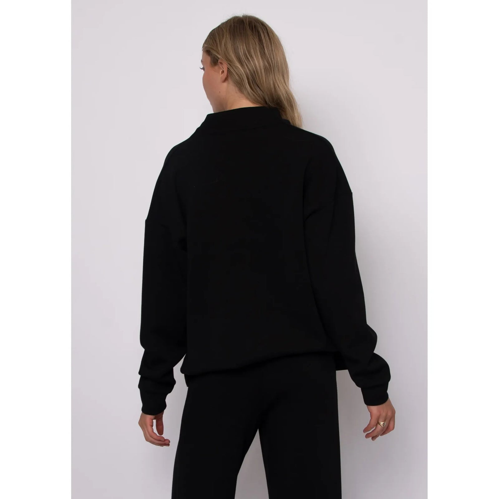 Back view of a black soft knit funnel neck top with long sleeves and a cozy stand-up collar.