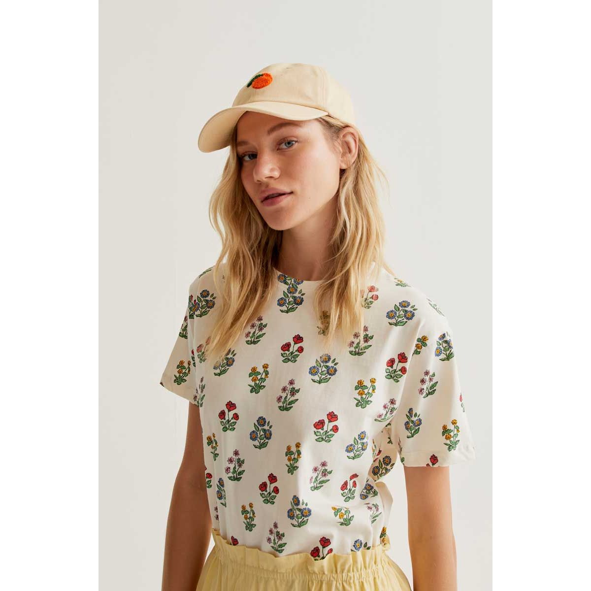 Model wearing Gardener Print Tee: white crew-neck shirt with colorful botanical floral print.