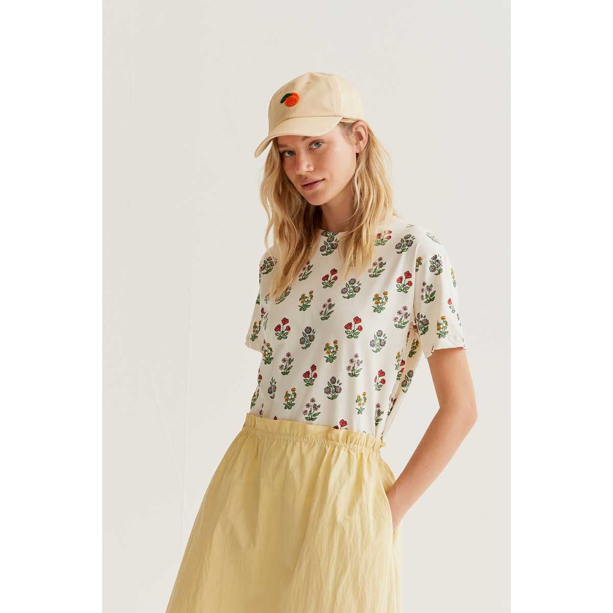 Gardener Print Tee: cream tee with whimsical multicoloured botanical print, worn with a pale yellow skirt.