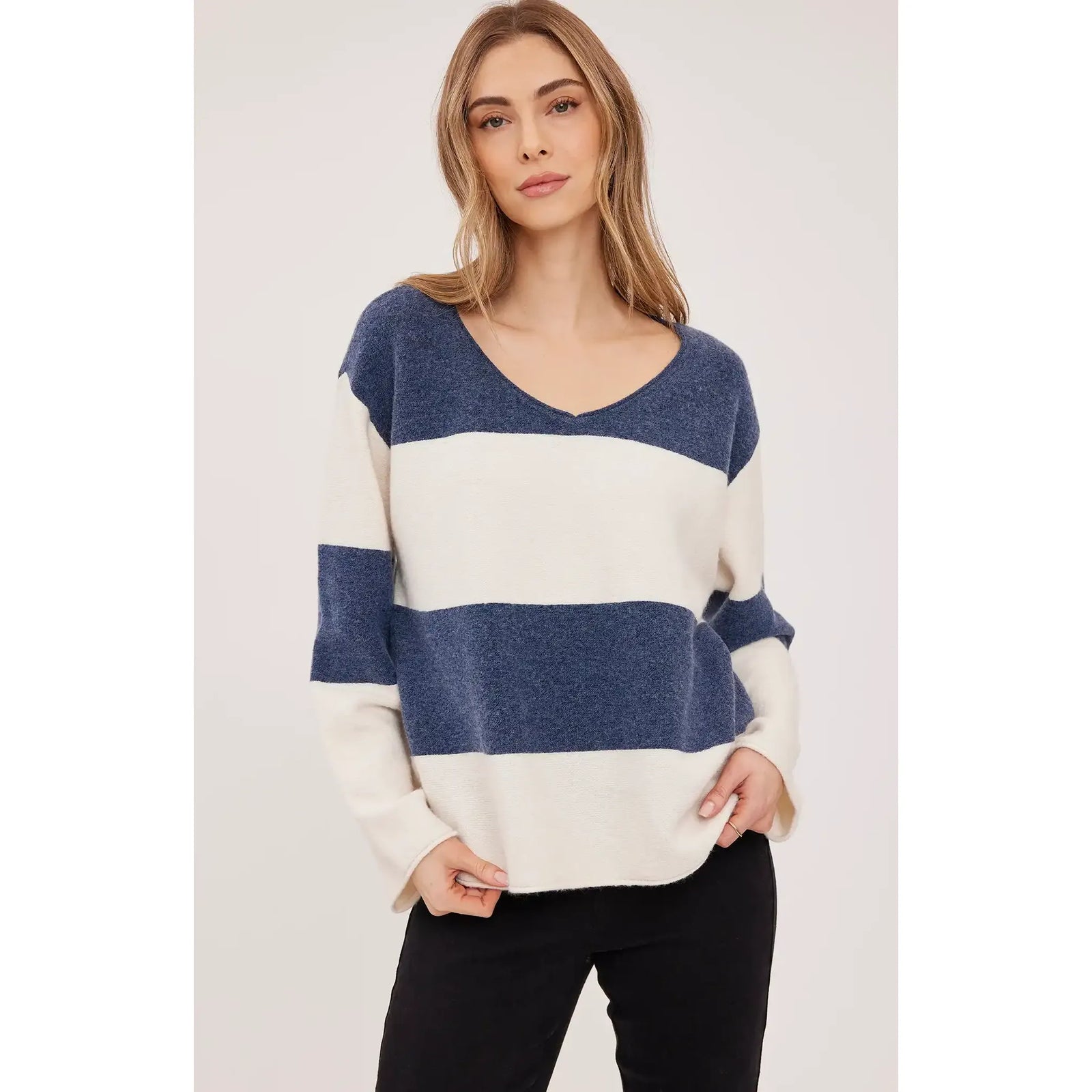 Oversized blue and cream striped V-neck sweater with soft textured knit and rolled edges for cozy comfort.