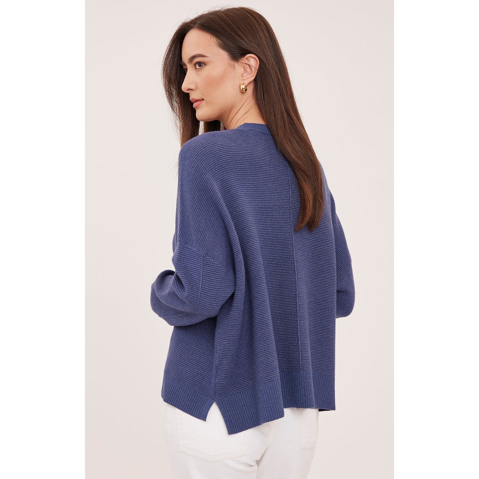 Back view of a navy waffle knit crewneck sweater with an oversized fit and side slit hem.