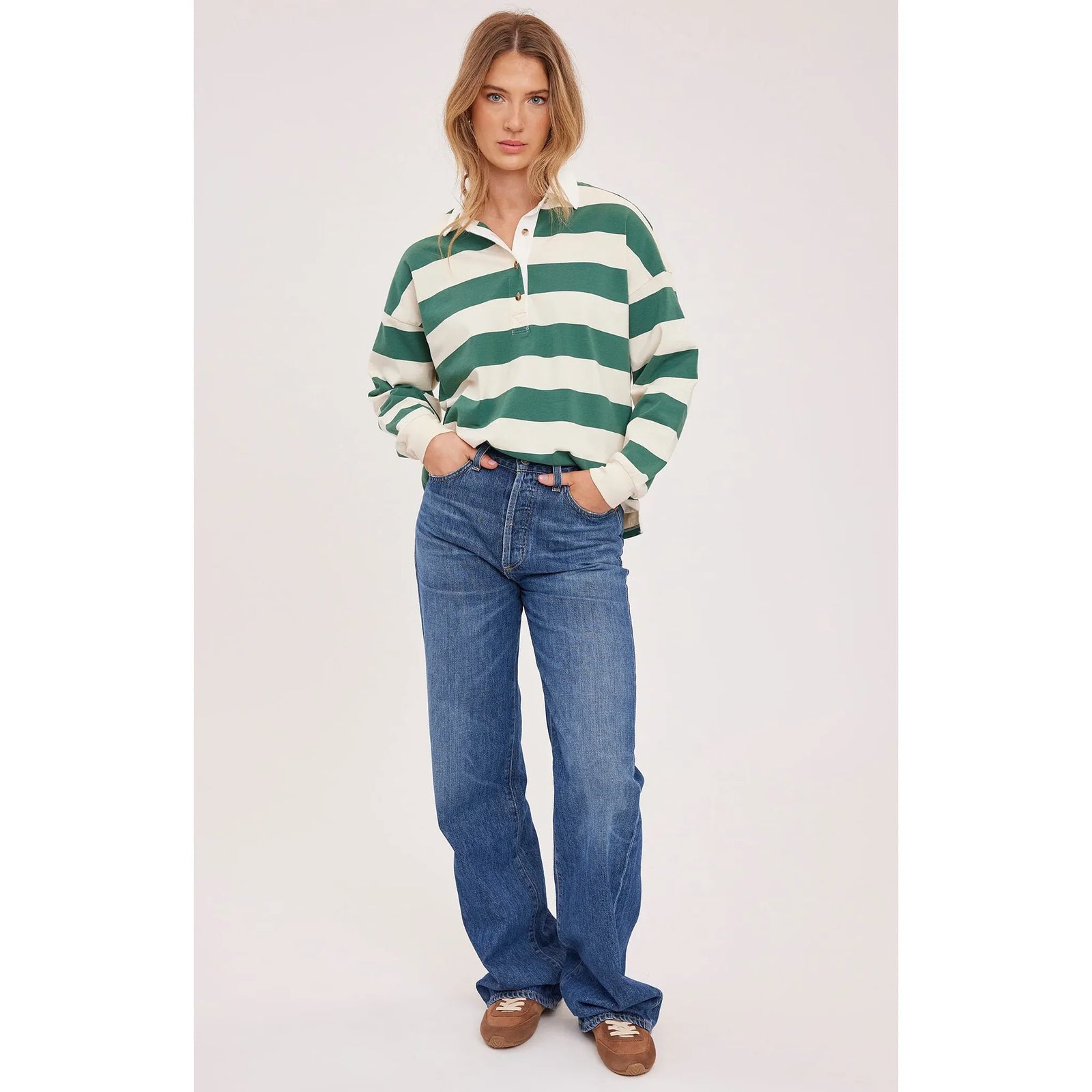 Model in green-and-white striped rugby shirt with contrasting collar and half-button placket, in blue jeans.