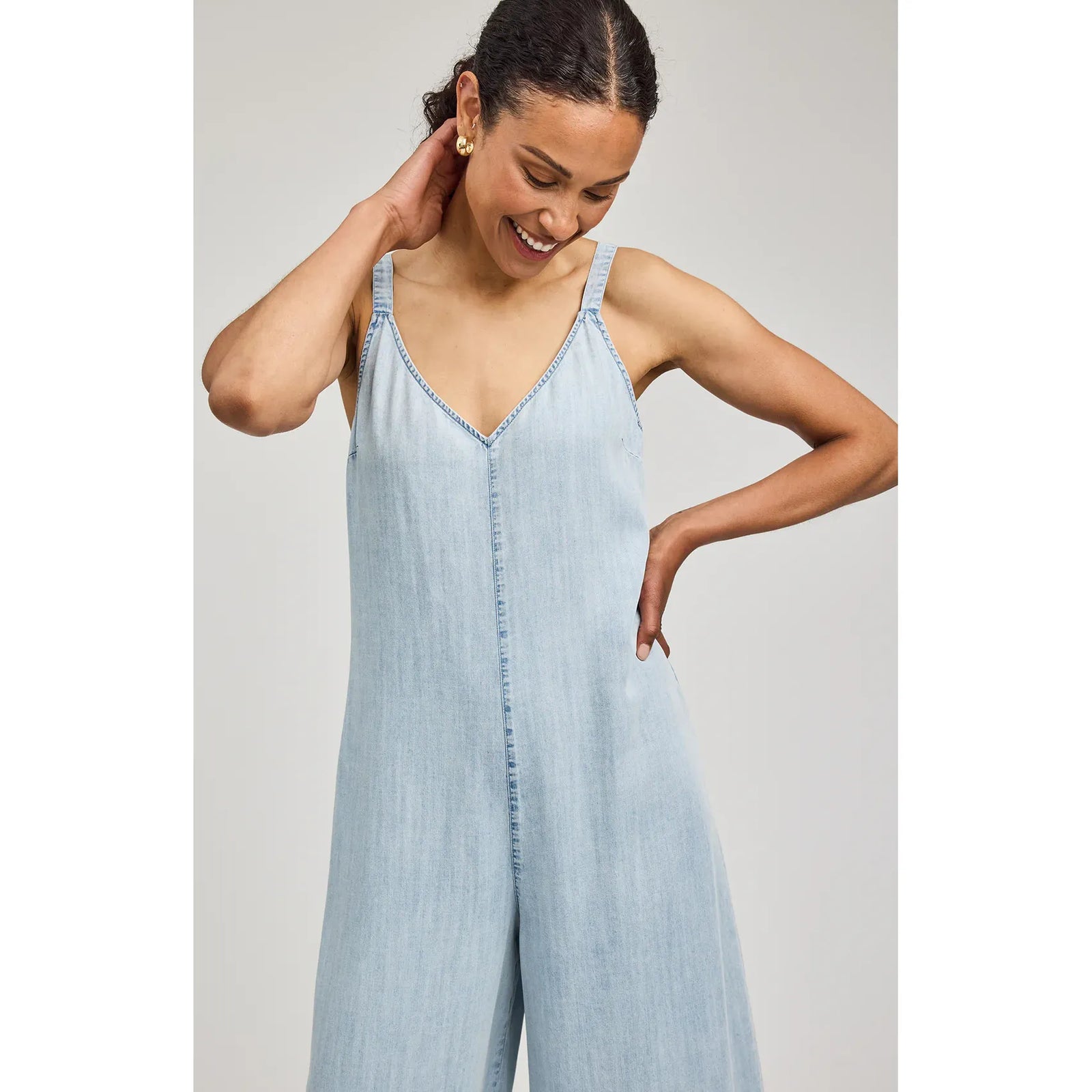 Cambry Jumpsuit in light denim with V-neck, thin straps, and wide-leg silhouette on a model.