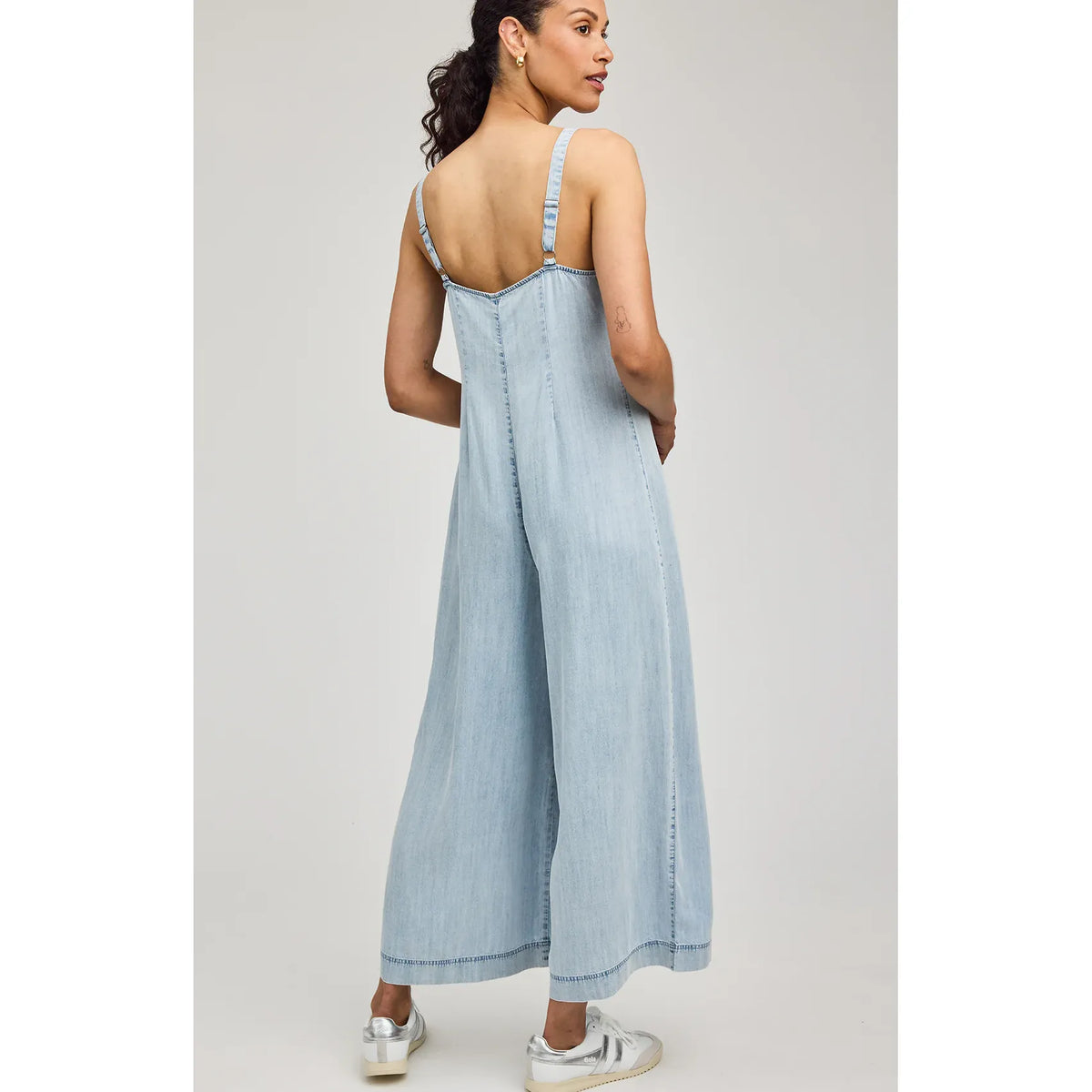Back view of a light-wash Gentle Fawn Cambry Jumpsuit with adjustable straps and wide legs.