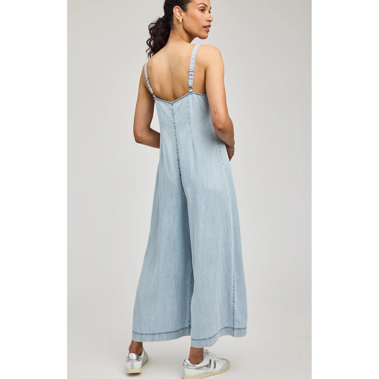 Back view of a light-wash Gentle Fawn Cambry Jumpsuit with adjustable straps and wide legs.