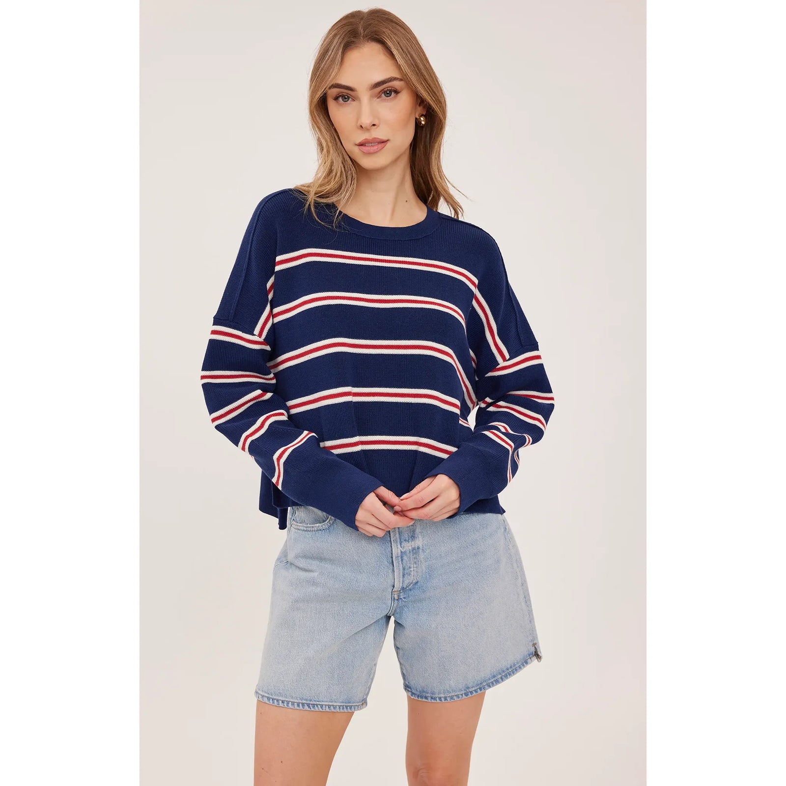 Oversized navy sweater with red and white stripes, featuring exposed seams and side slits for a cozy, stylish look.