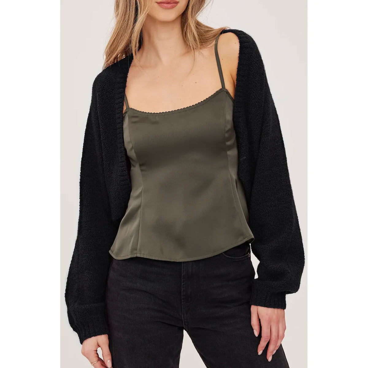 Black cropped bouclé cardigan with voluminous sleeves and fitted rib cuffs, worn open over a green camisole.