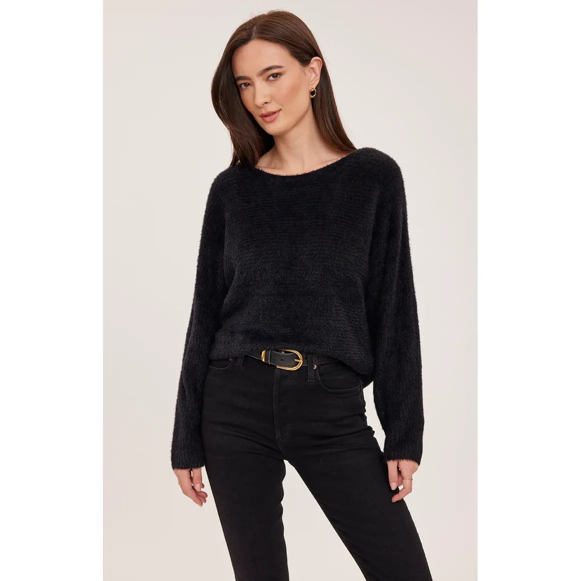 Black chunky knit sweater with wide boat neckline and dolman sleeves, styled belted with black denim jeans.