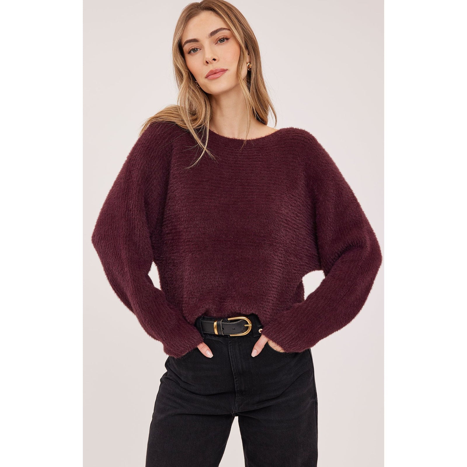 Plush deep Port Mara sweater with wide boat neckline and dolman sleeves, styled with dark denim and belt.