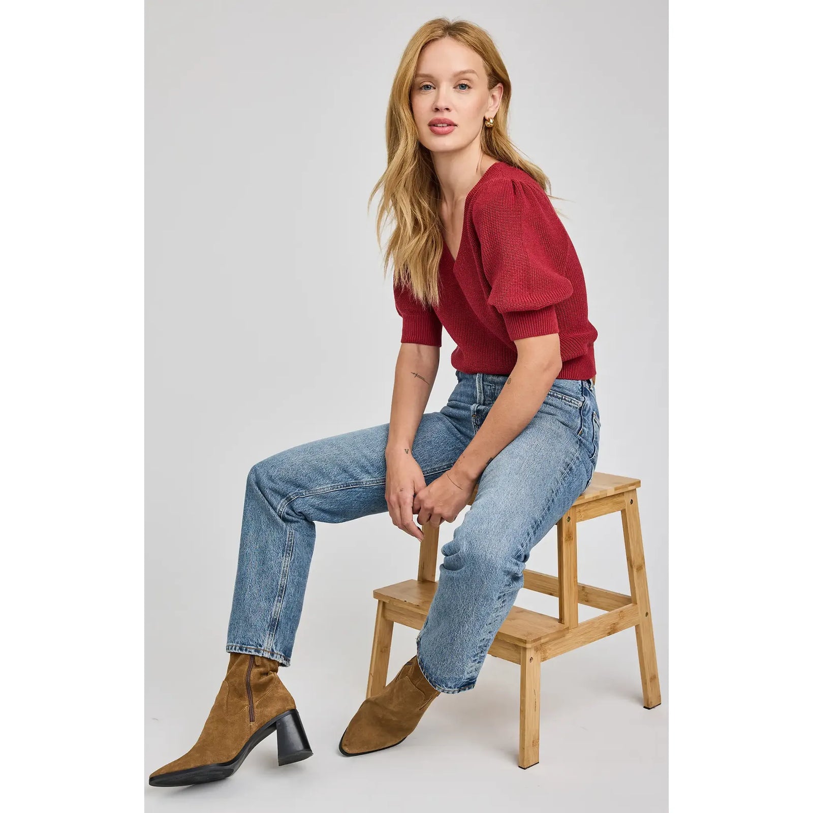 Gentle Fawn Phoebe V-Neck Sweater in red knit with puff sleeves on a model wearing blue jeans.