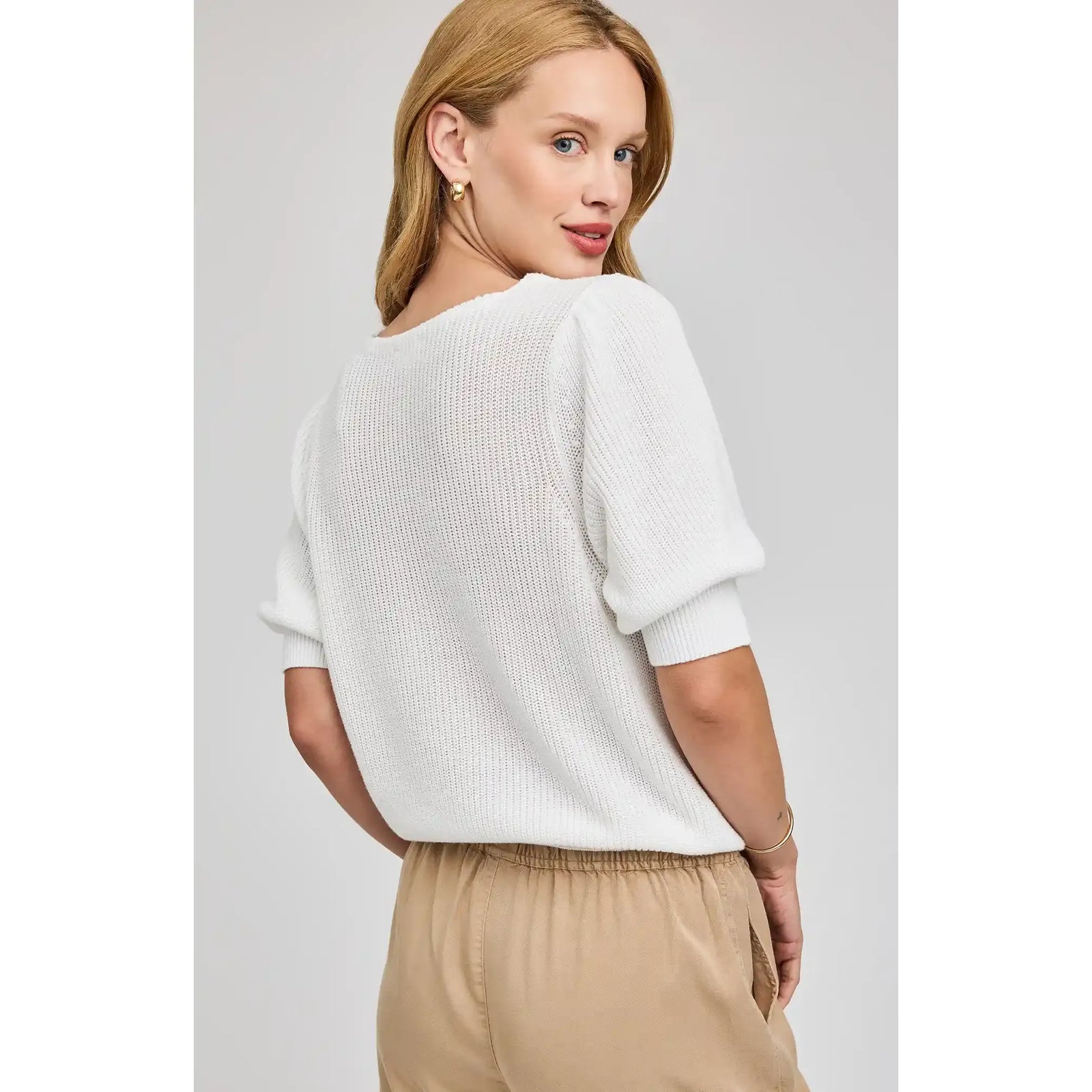 Model wearing white knit Phoebe V-Neck Sweater with puff sleeves.