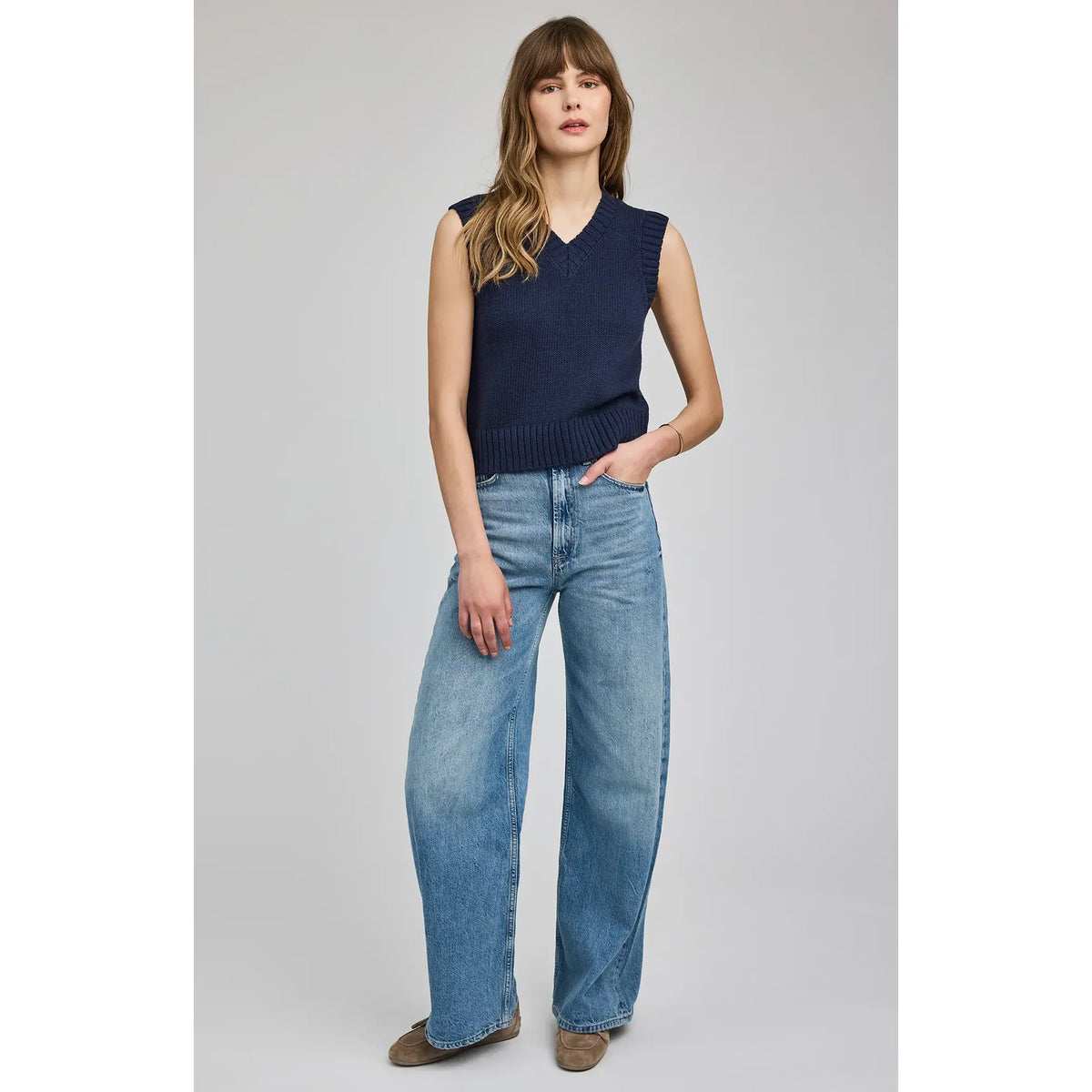 Model wearing Gentle Fawn Pippa V-Neck Tank: navy sleeveless knit with V-neck and ribbed hem, wide-leg jeans.