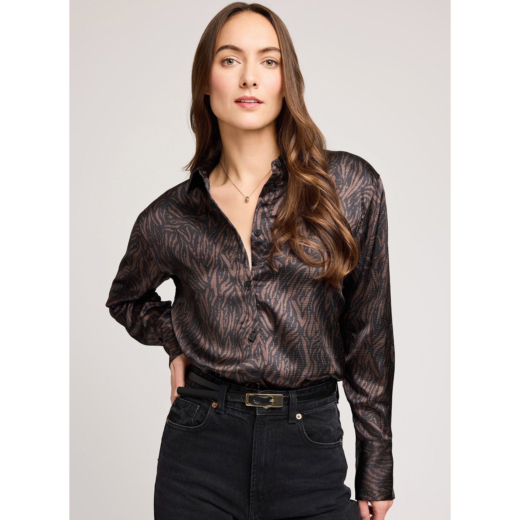 Model wearing Gentle Fawn Simone black hammered-satin blouse with long sleeves and subtle pattern, tucked into jeans.