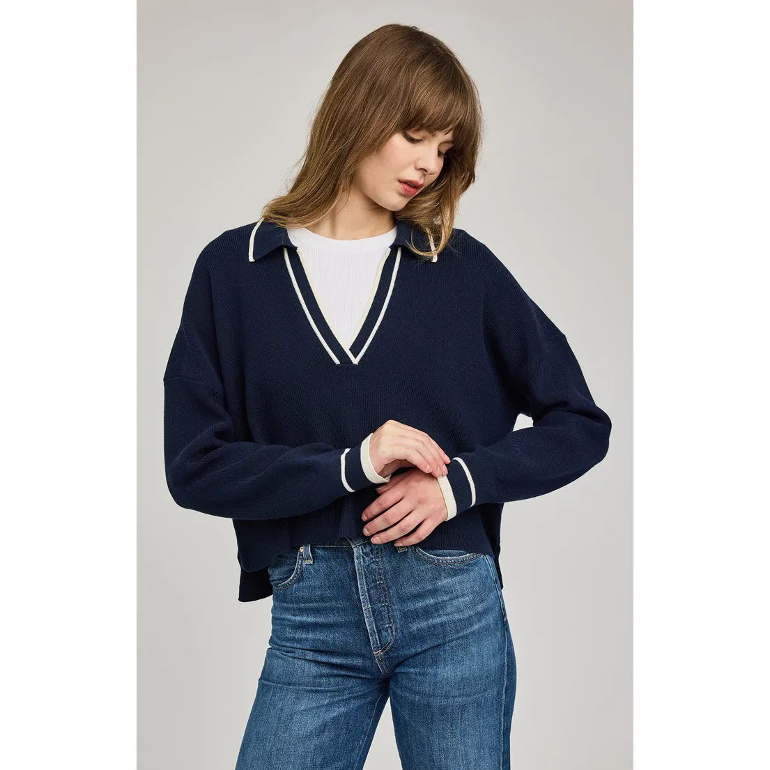 Gentle Fawn Tristan V-Neck Sweater in navy with white stripe trim at the V-neck and cuffs, worn with jeans.