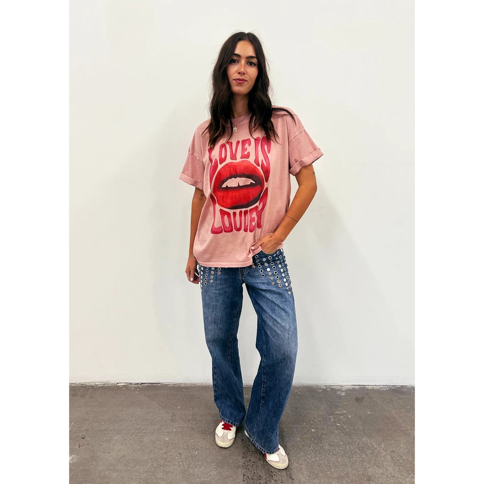 Pink oversized boyfriend tee with bold red LOVE IS LOUDER lips graphic, paired with wide-leg jeans.