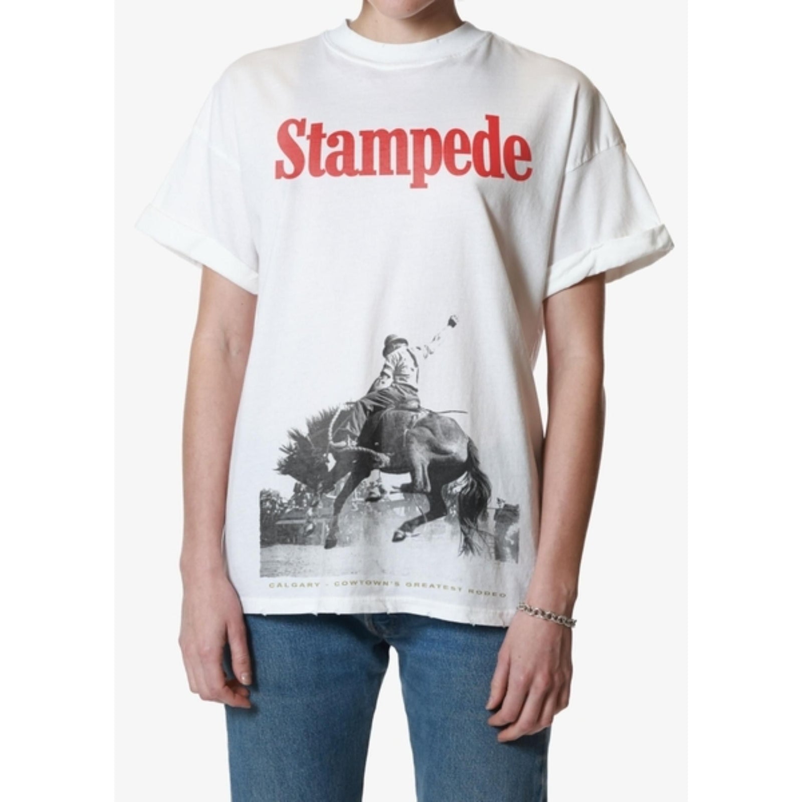 Girl wearing white oversized tee with bold red Stampede text and vintage horse graphic.