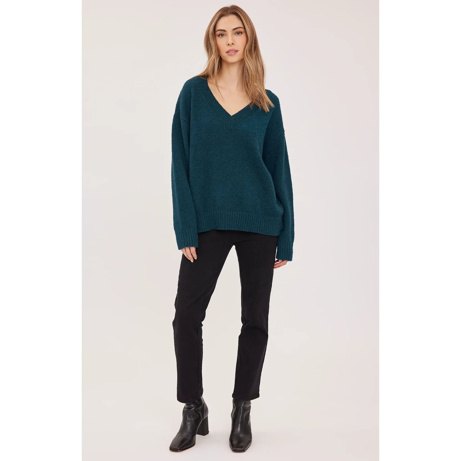 Teal oversized v-neck sweater with soft bouclé texture, ribbed cuffs and hem, styled with black pants and ankle boots.