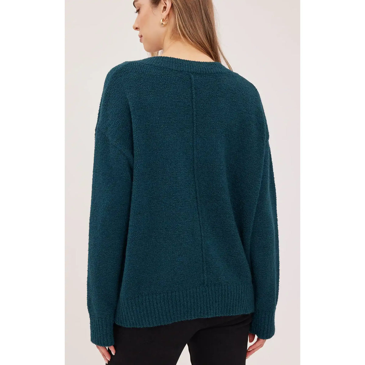 Back view of a dark teal oversized bouclé sweater featuring a ribbed hem, textured knit fabric, and relaxed fit.
