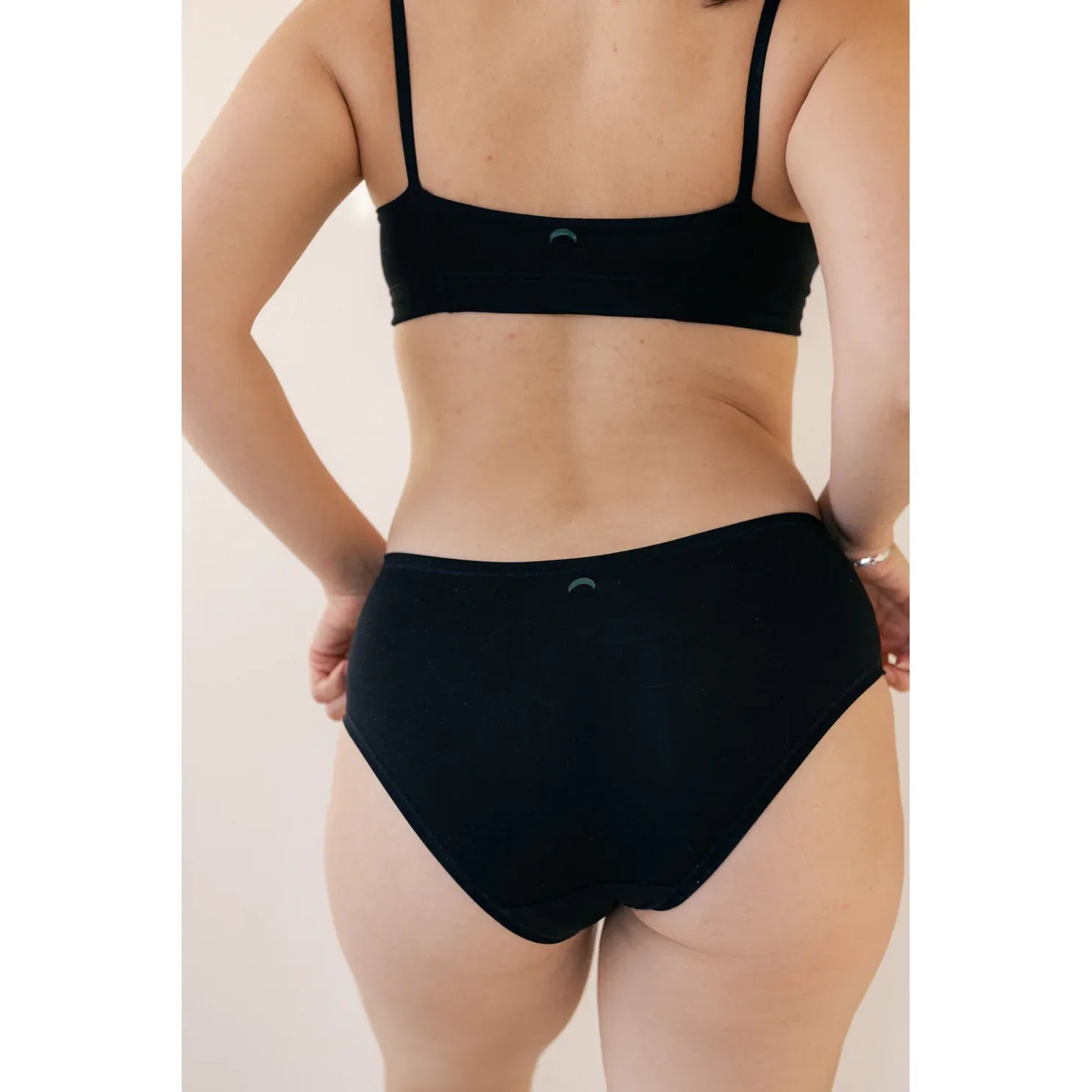 Back view of black hardware-free Huha Tata Mineral Bralette with elastic straps and broad underband.