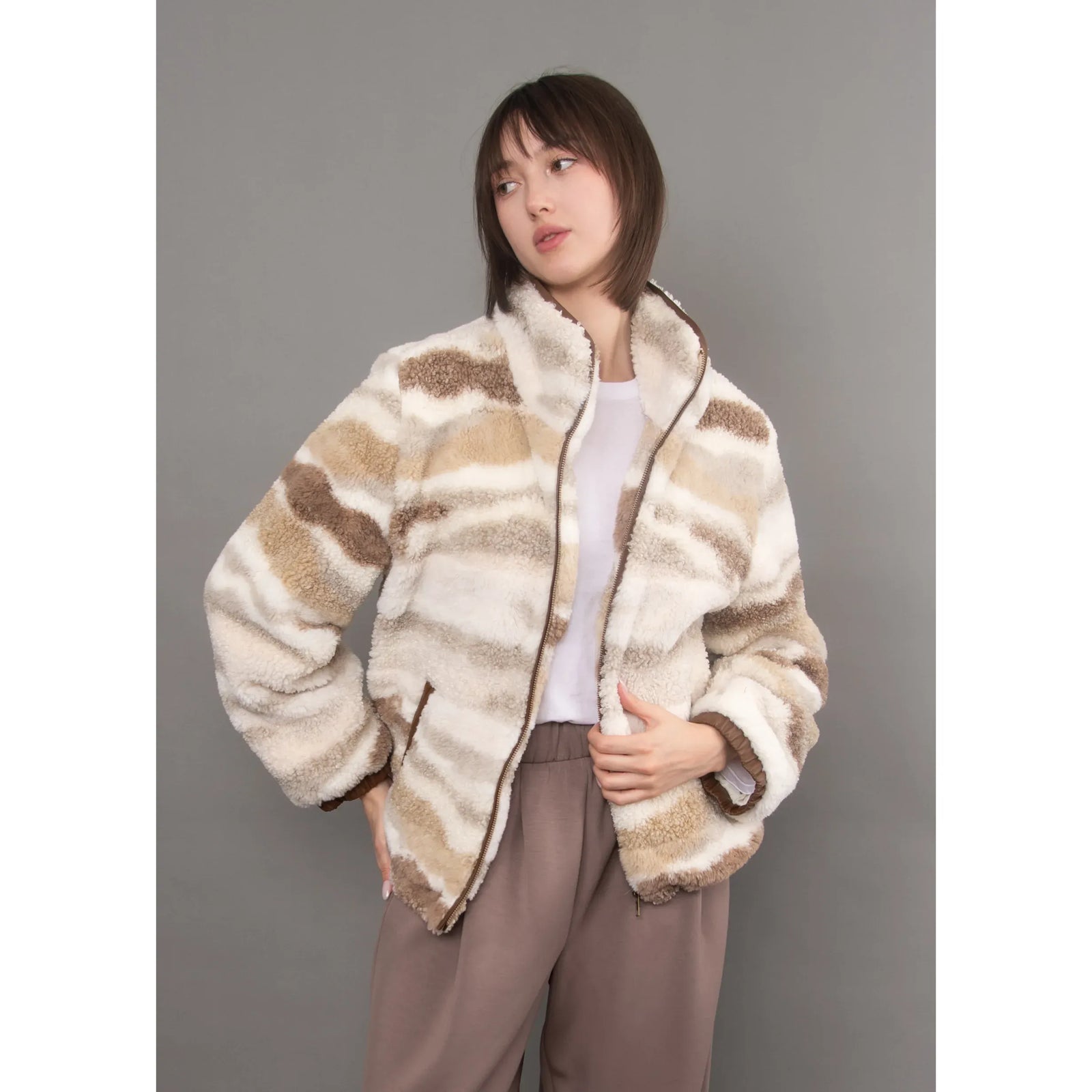 Plush patterned sherpa jacket with brown and cream stripes, featuring a full zip, velvet trim details, and an easy casual silhouette.
