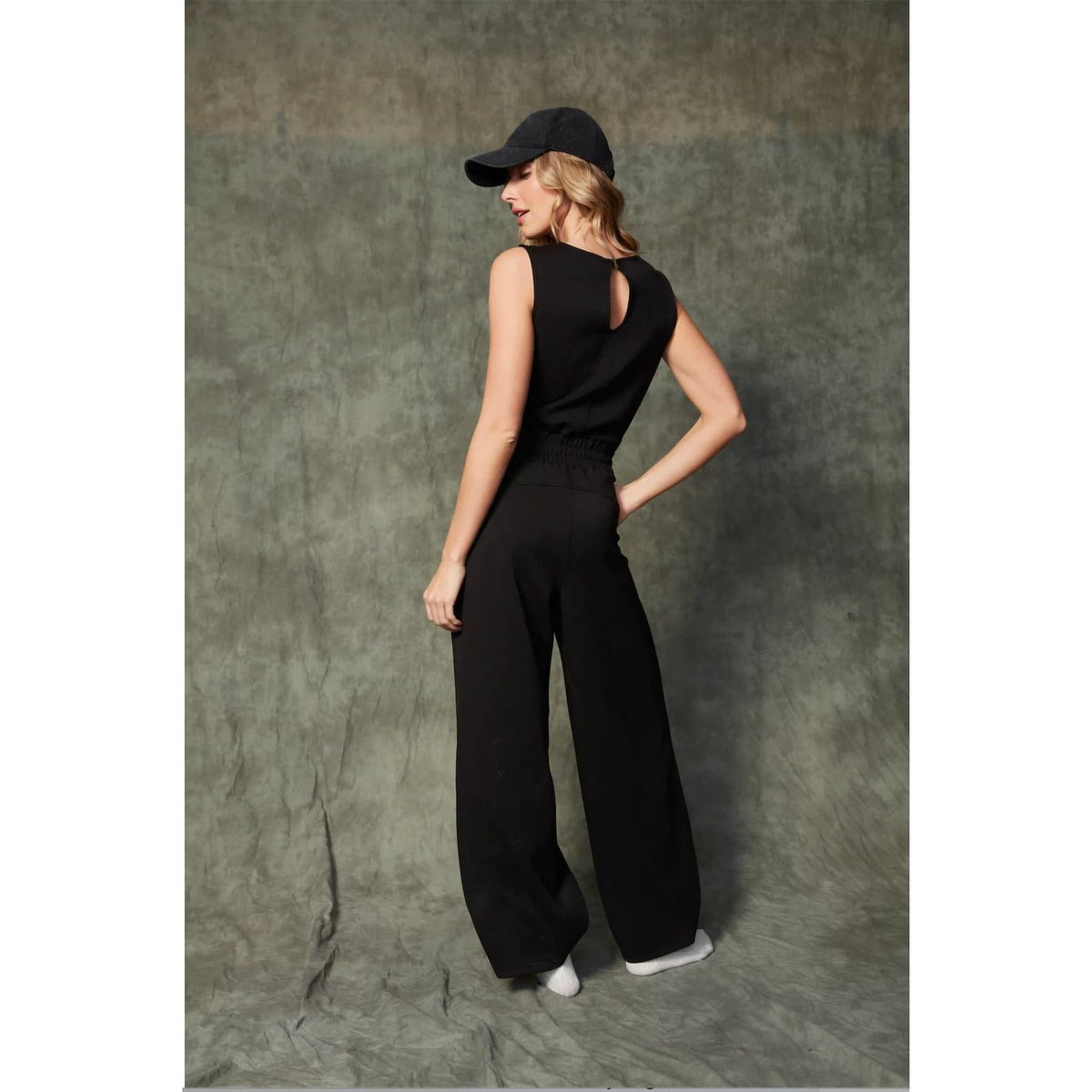 Juniva Soft Knit Jumpsuit on model—sleek sleeveless black knit with long wide legs and back keyhole.