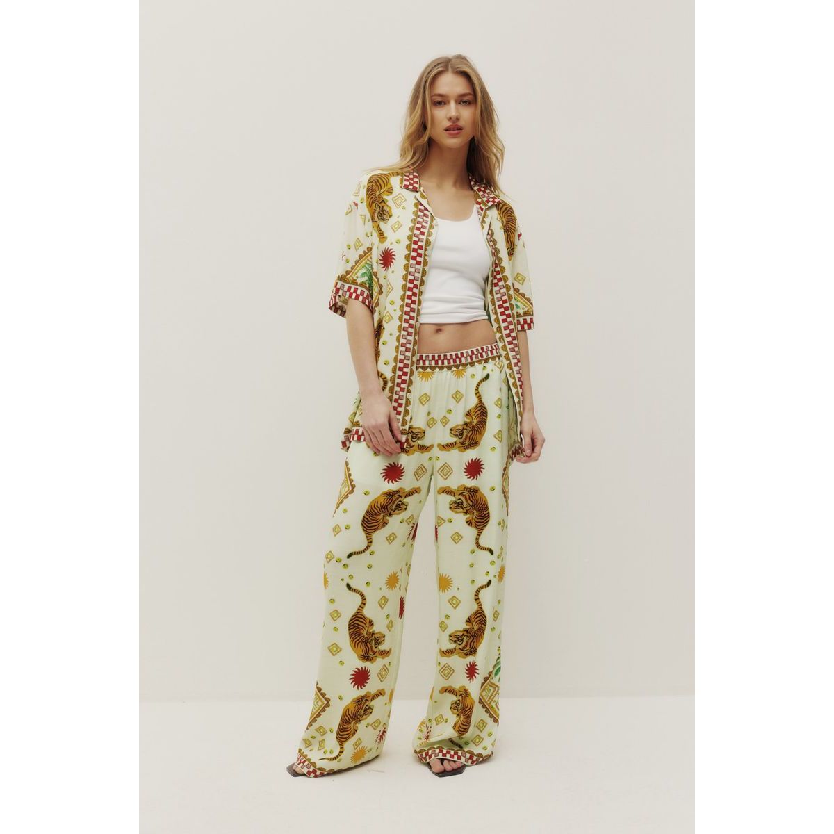 Model wearing cream tiger-print Kuwalla Beach Shirt set with matching wide-leg pants.