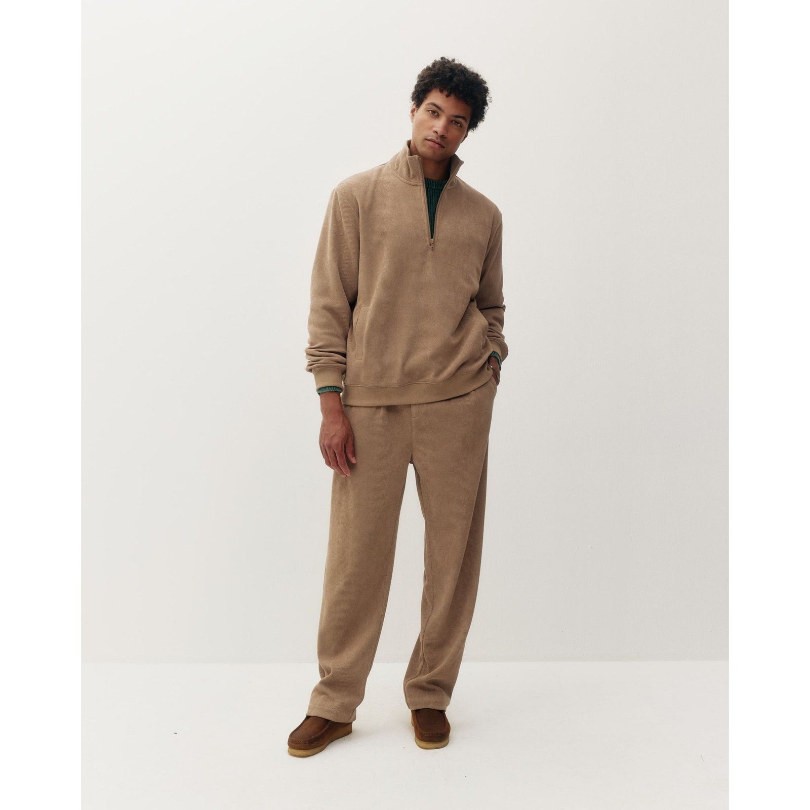 Man wearing a beige chenille 1/4 zip sweatshirt and matching pants for a cozy, modern casual look.