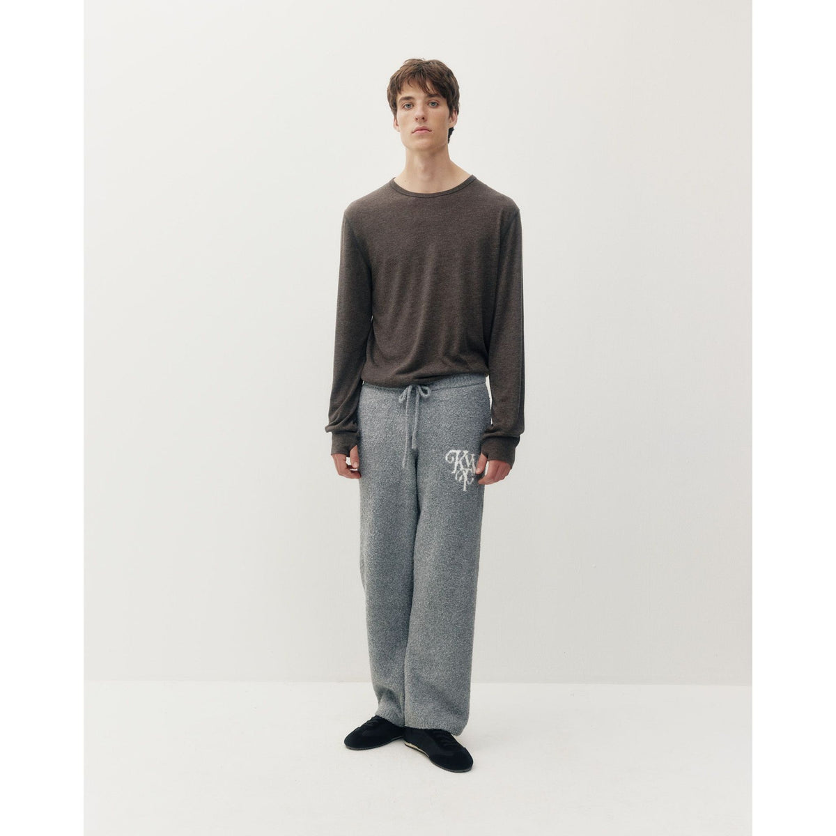 Model wearing a dark heathered thermal long sleeve tee paired with grey drawstring sweatpants featuring a white monogram logo.