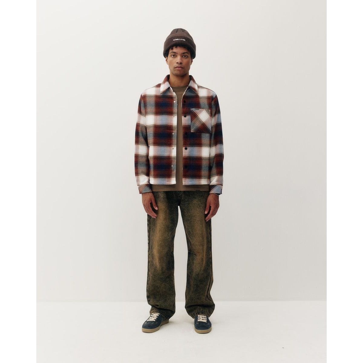 Man wearing heavyweight plaid shacket in red, white, and blue with brown beanie and Acid wash jeans.
