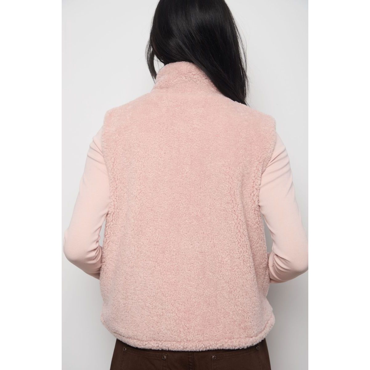 Back view of a light pink faux fur zip-up vest with a high collar, styled as a warm transitional layer over a matching long-sleeve top.