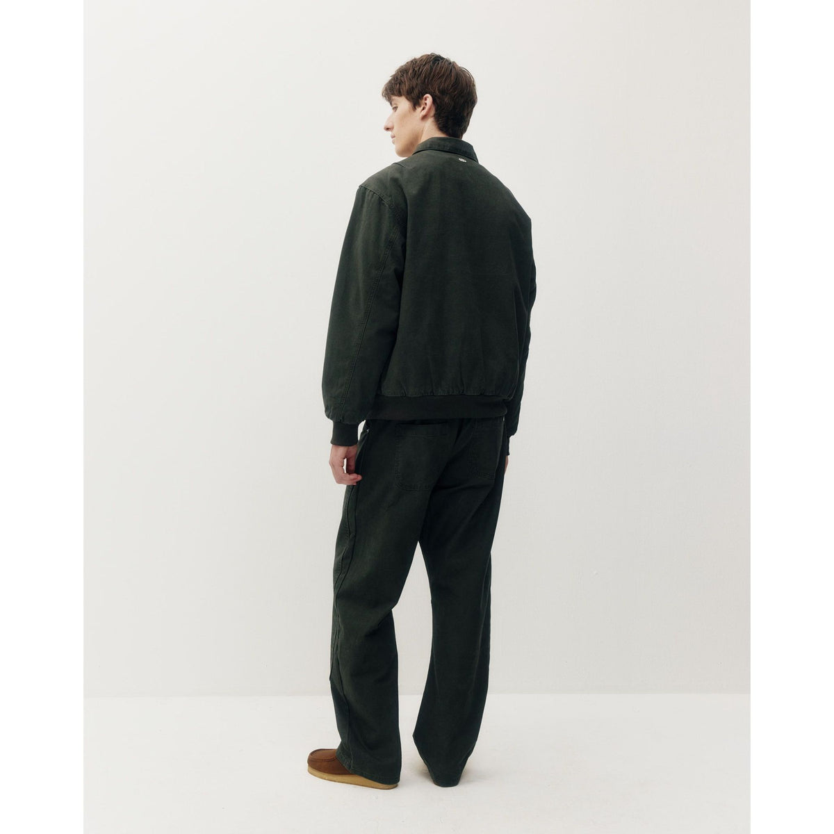 Back view of a dark green cotton Oxford Bomber jacket with structured collar and ribbed cuffs, paired with matching utility trousers.