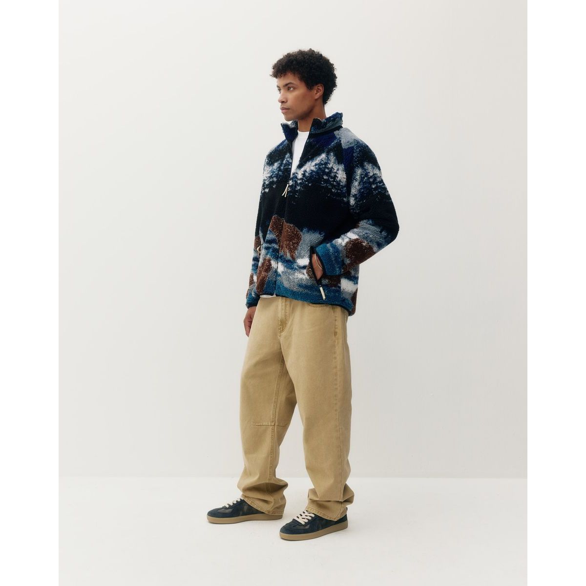 Model wearing printed sherpa fleece jacket featuring bears in the wild design, paired with beige cargo pants and sneakers for cozy, stylish layering.
