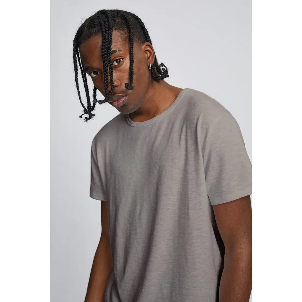 Model wearing Kuwalla Slub Hi-Lo Tee in gray, quad-blended fabric, curved hi-lo hem, slub texture.