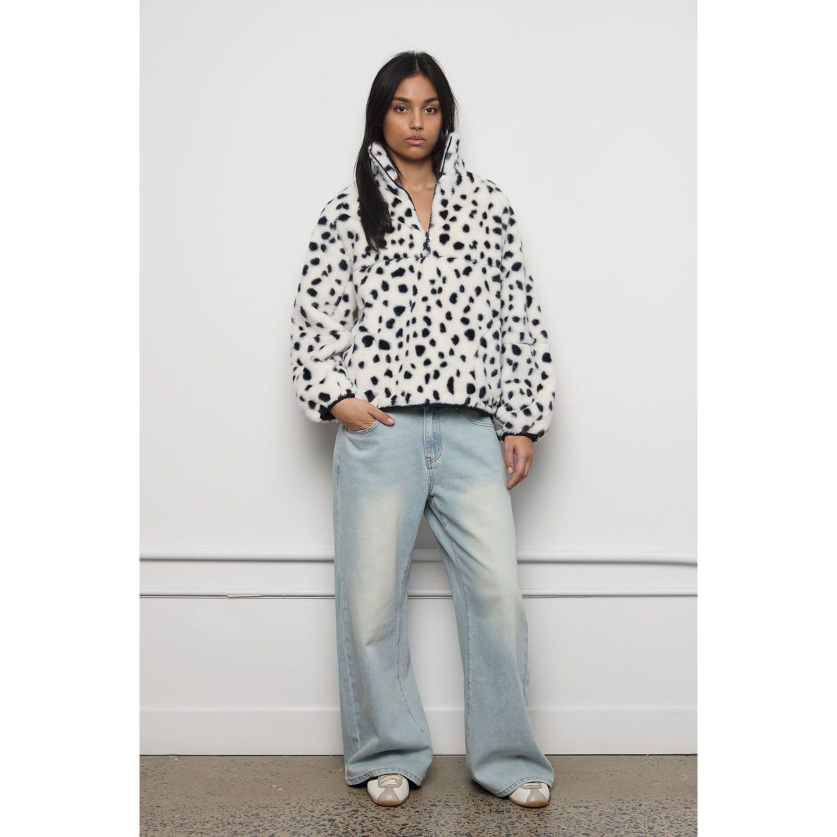 White faux fur zip-up jacket with black spotted print, featuring a plush texture and high collar for modern streetwear warmth.