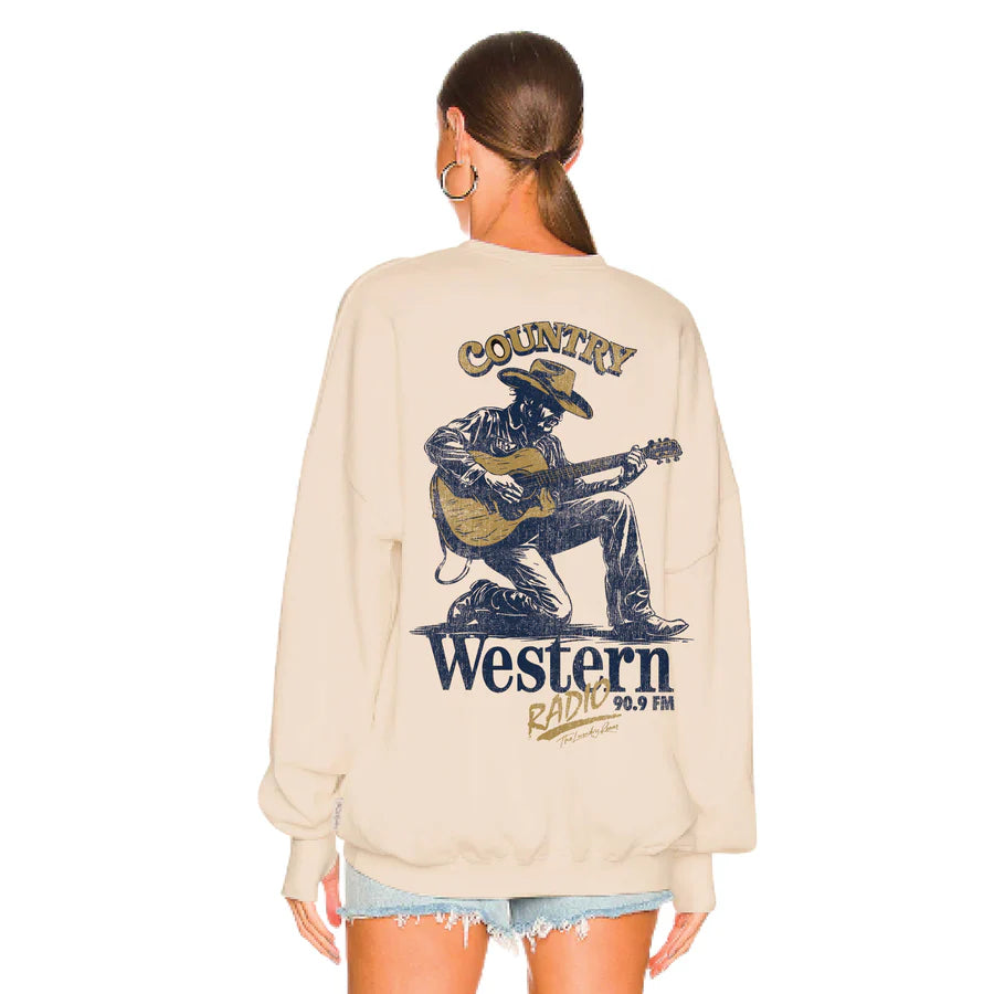 Beige sweatshirt with a graphic of a cowboy playing guitar and text on the back, worn by a person.