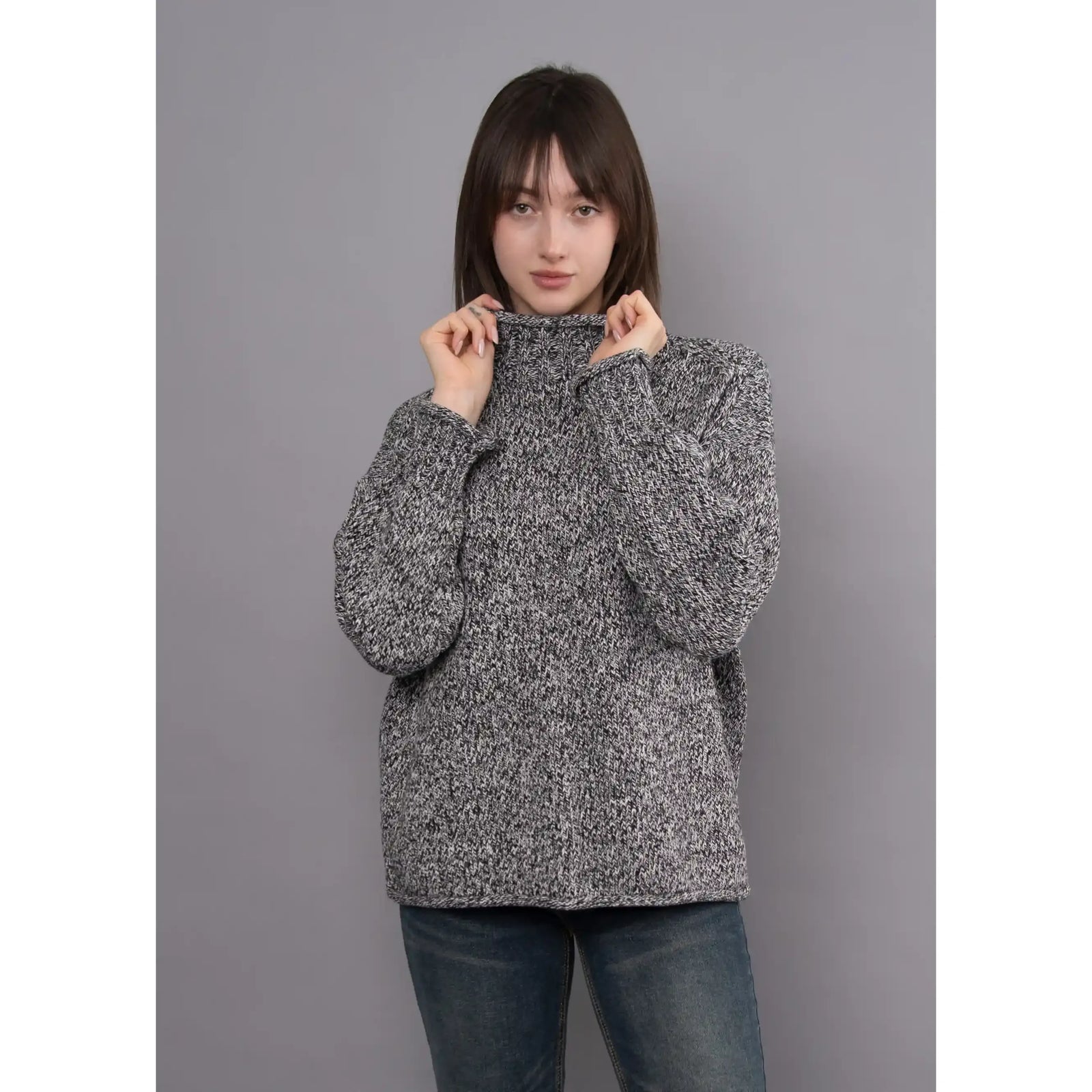 Model wearing a black twist funnel neck sweater with a textured multi-tonal knit pattern and a high stand-up collar.