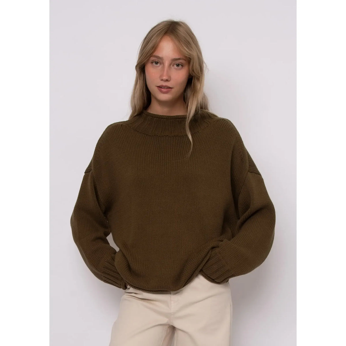 Model wears an olive green Lucretia funnel neck sweater with ribbed collar and dropped shoulders.