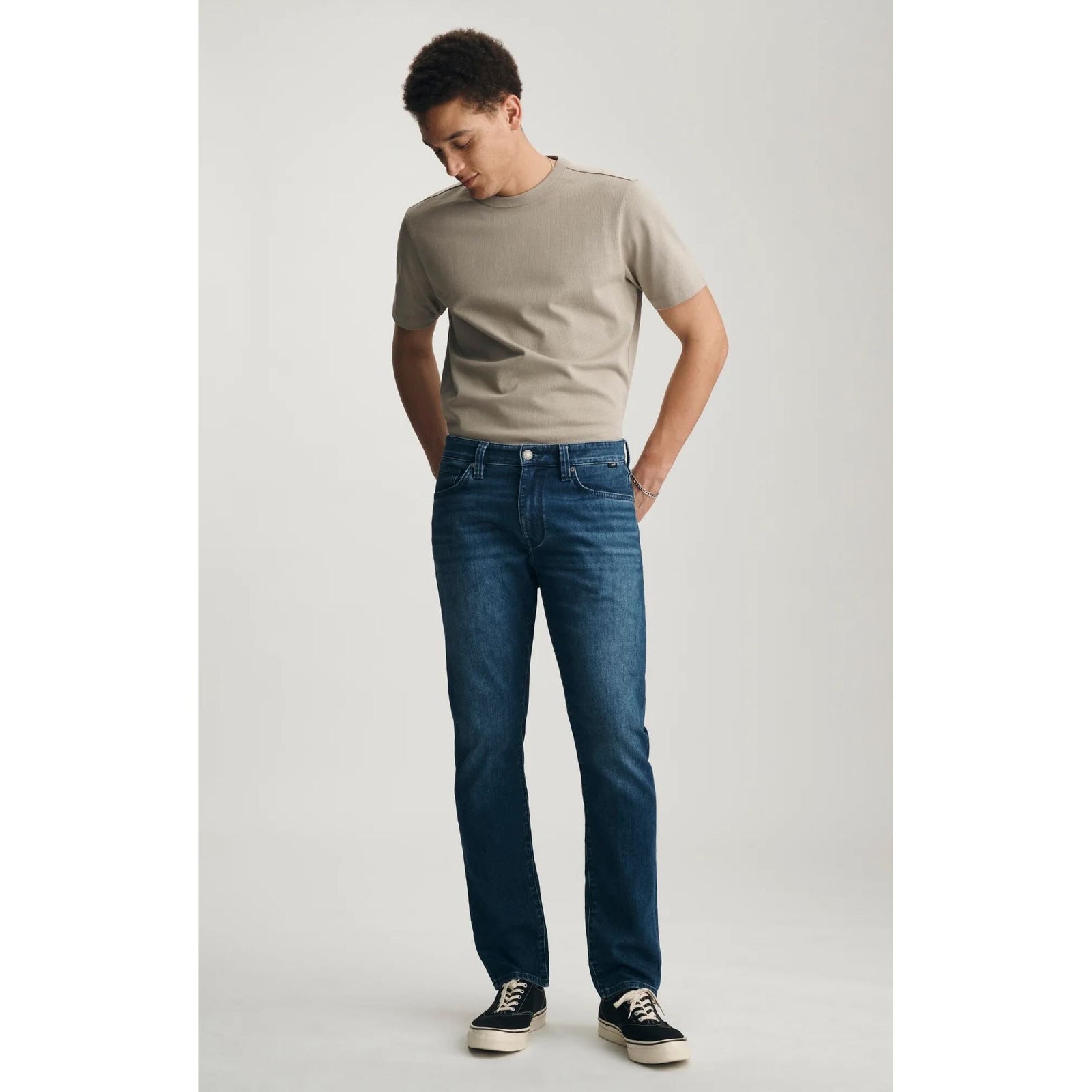 Mavi Marcus Dark Air-Lite Denim jeans in dark wash on a male model wearing a beige T-shirt and sneakers.