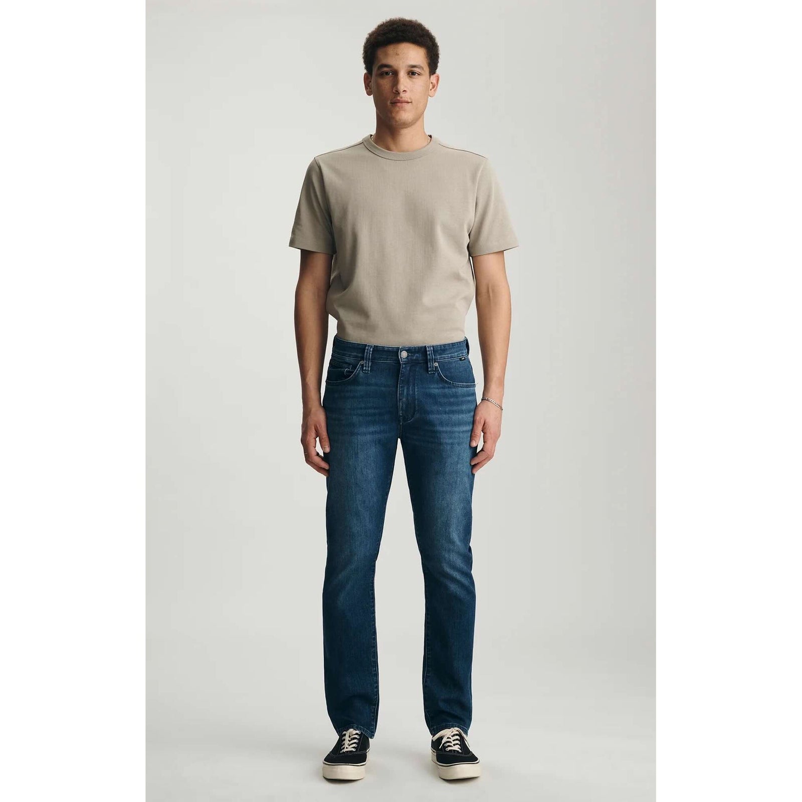 Mavi Marcus Dark Air-Lite Denim jeans in dark wash on a male model wearing a beige T-shirt and sneakers.
