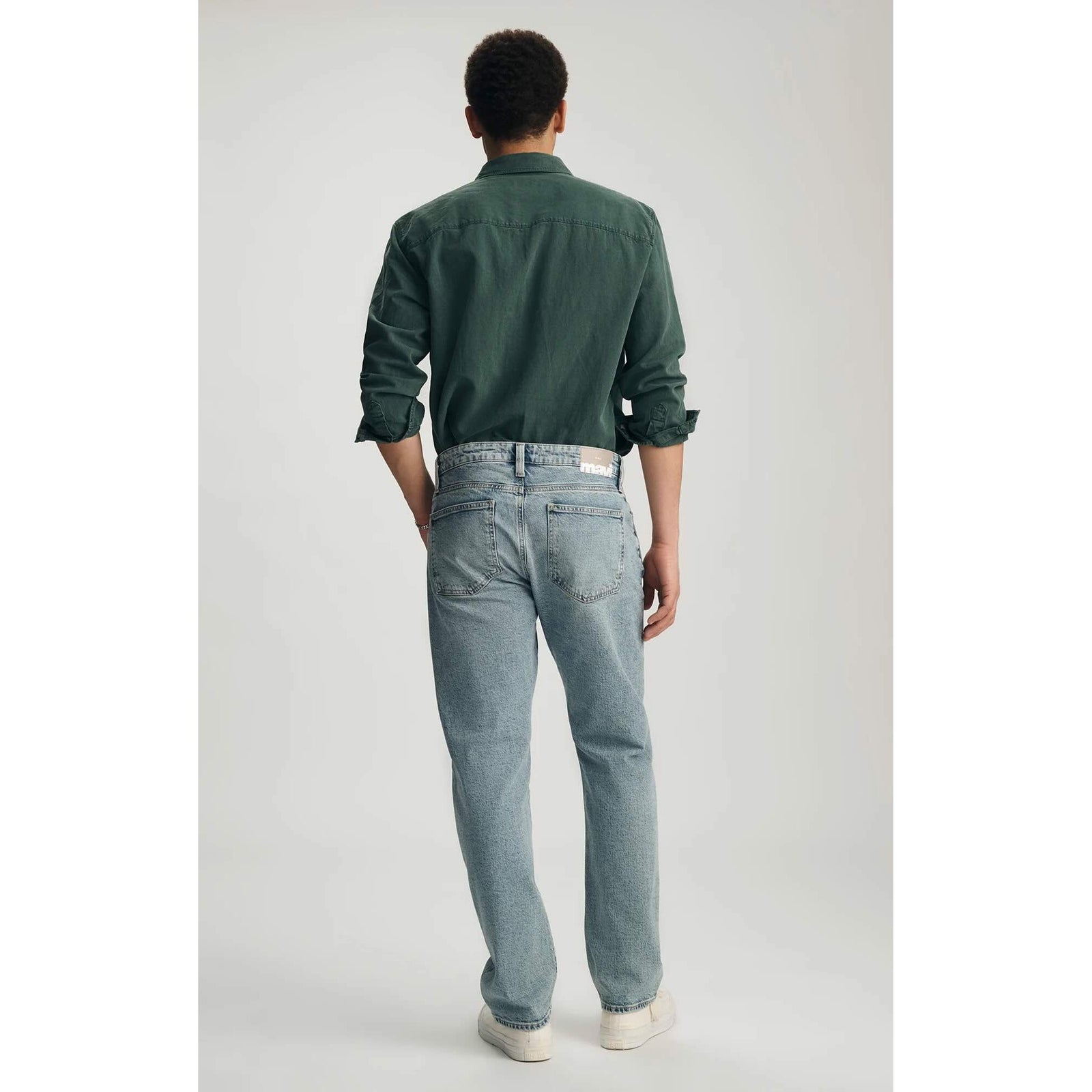 Back view of a male model wearing Mavi Zach Lt Shaded Classic Blue Denim jeans in a straight leg, light wash.