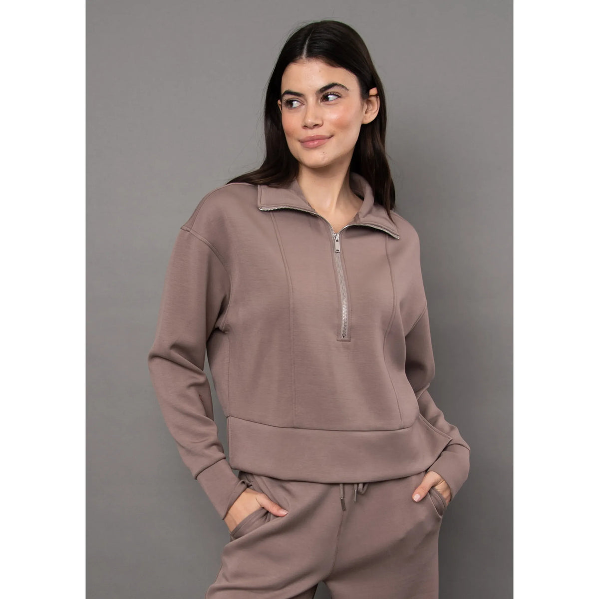Woman wearing a dusty rose soft knit zip-up top with a quarter-zip collar and relaxed fit, paired with matching pants.