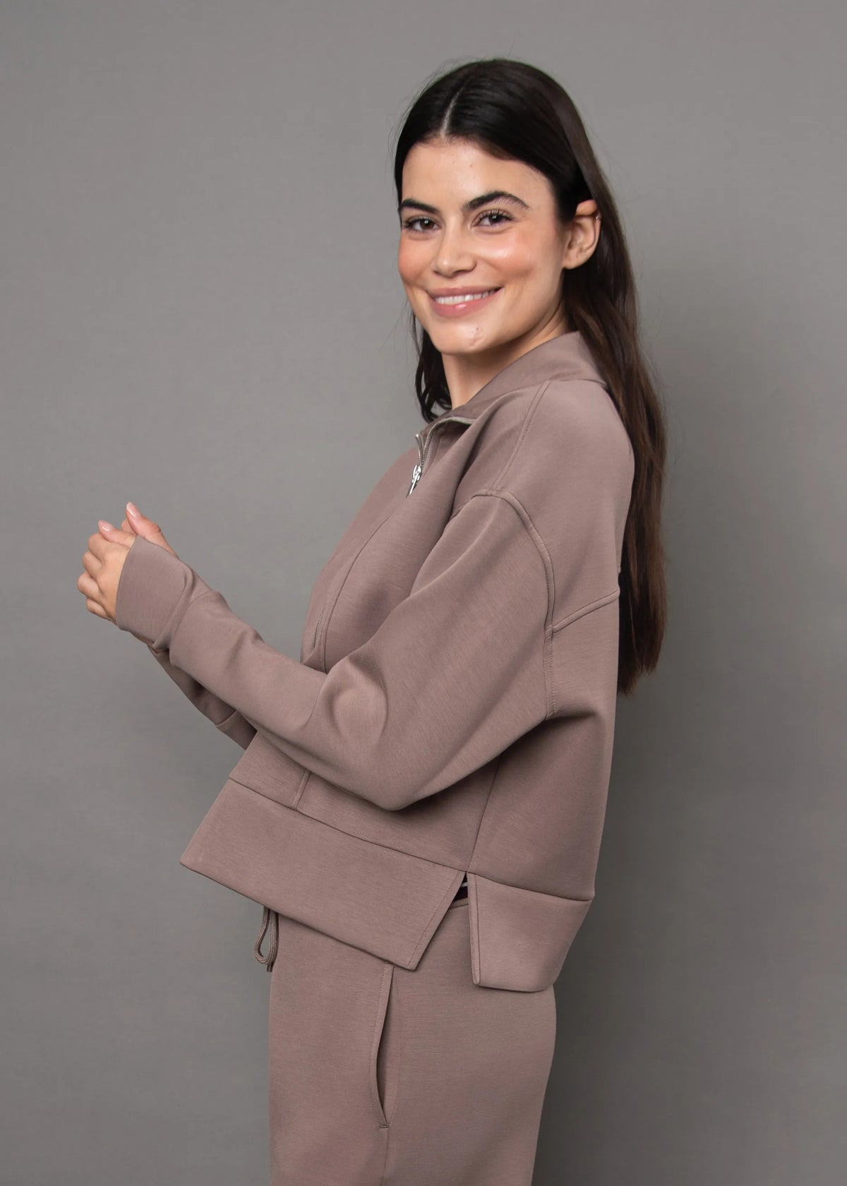 Woman wearing a dusty rose soft knit zip-up top with a quarter-zip collar and matching loungewear pants.