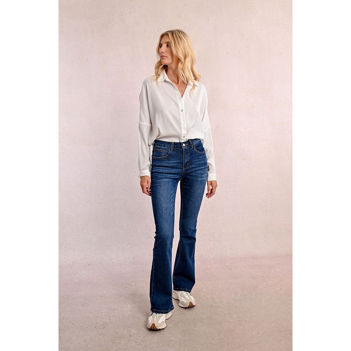 Molly Bracken Bootcut in Brut Denim: high-waisted blue bootcut jeans with pockets worn by a model in a white blouse.