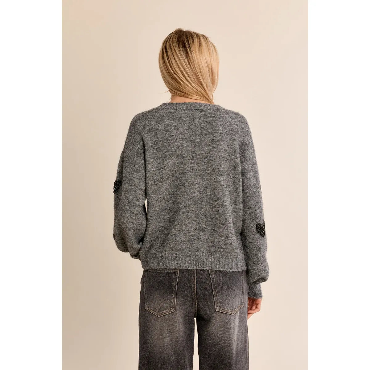 Back view of gray Molly Bracken heart cardigan with balloon sleeves and black heart details on sleeves, paired with dark jeans.