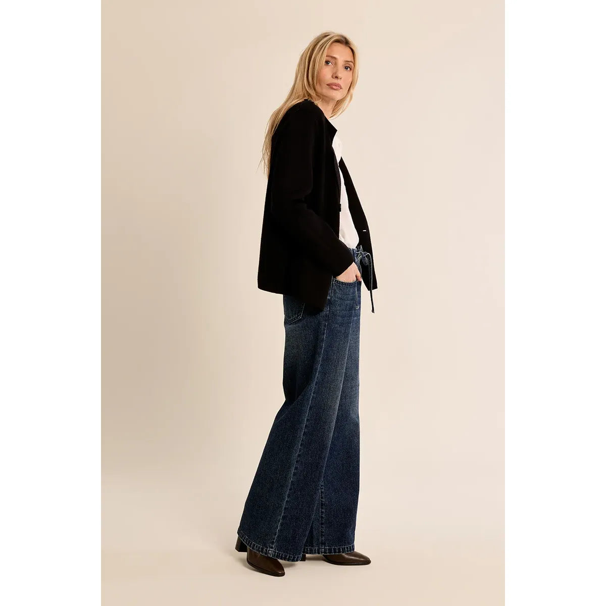 Woman wearing a black Molly Bracken knit jacket with a cropped silhouette, styled over a white top and wide-leg jeans.